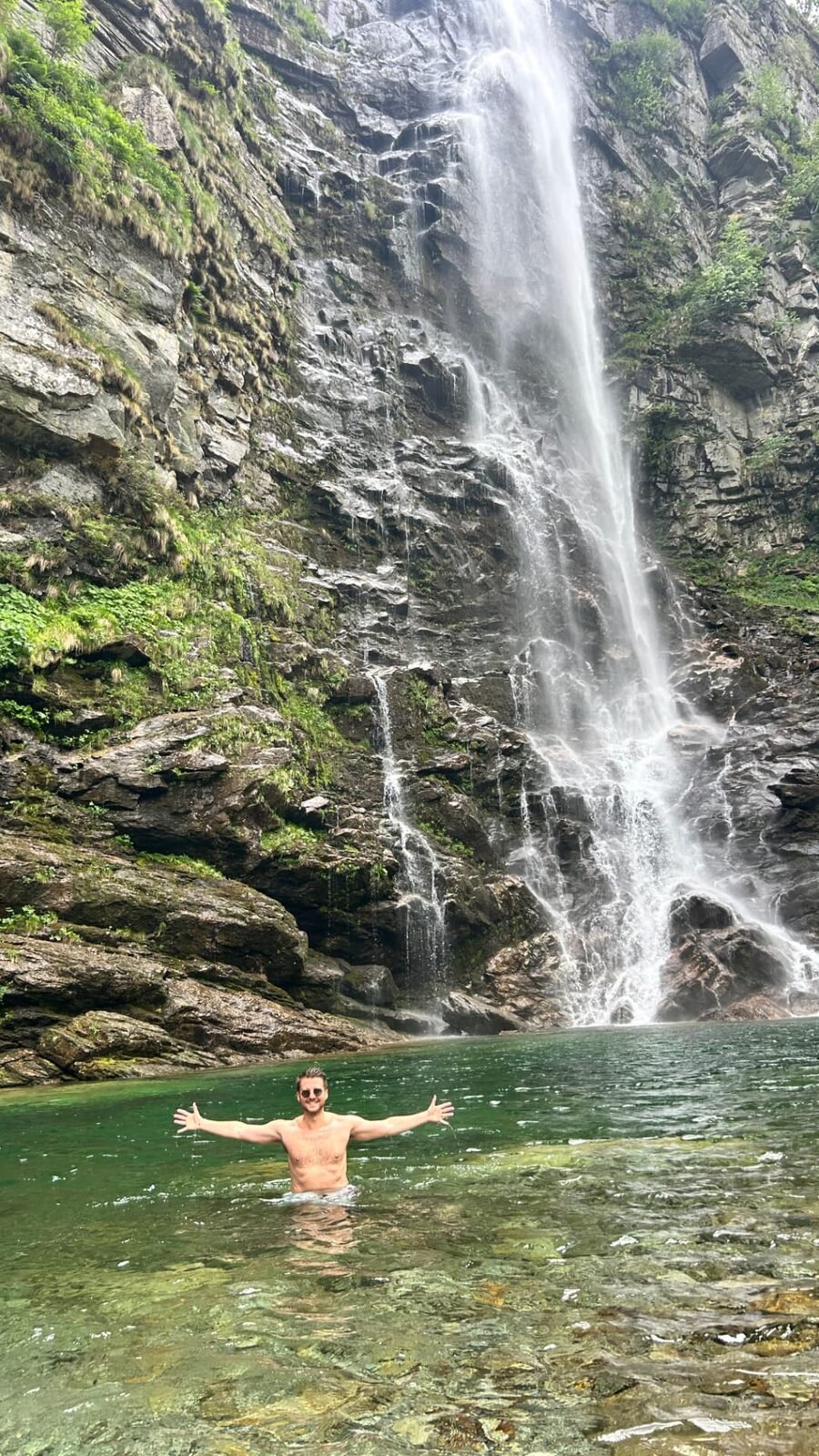 Fiorenzo presso una cascata in Ticino, a braccia aperte
